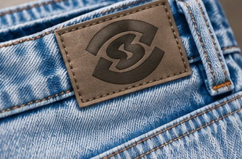 Nahaufnahme des Leder-Patches am Bund mit dem oneofone-Logo.